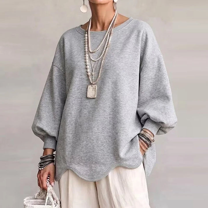 Woman wearing light gray oversized sweatshirt with wavy hem