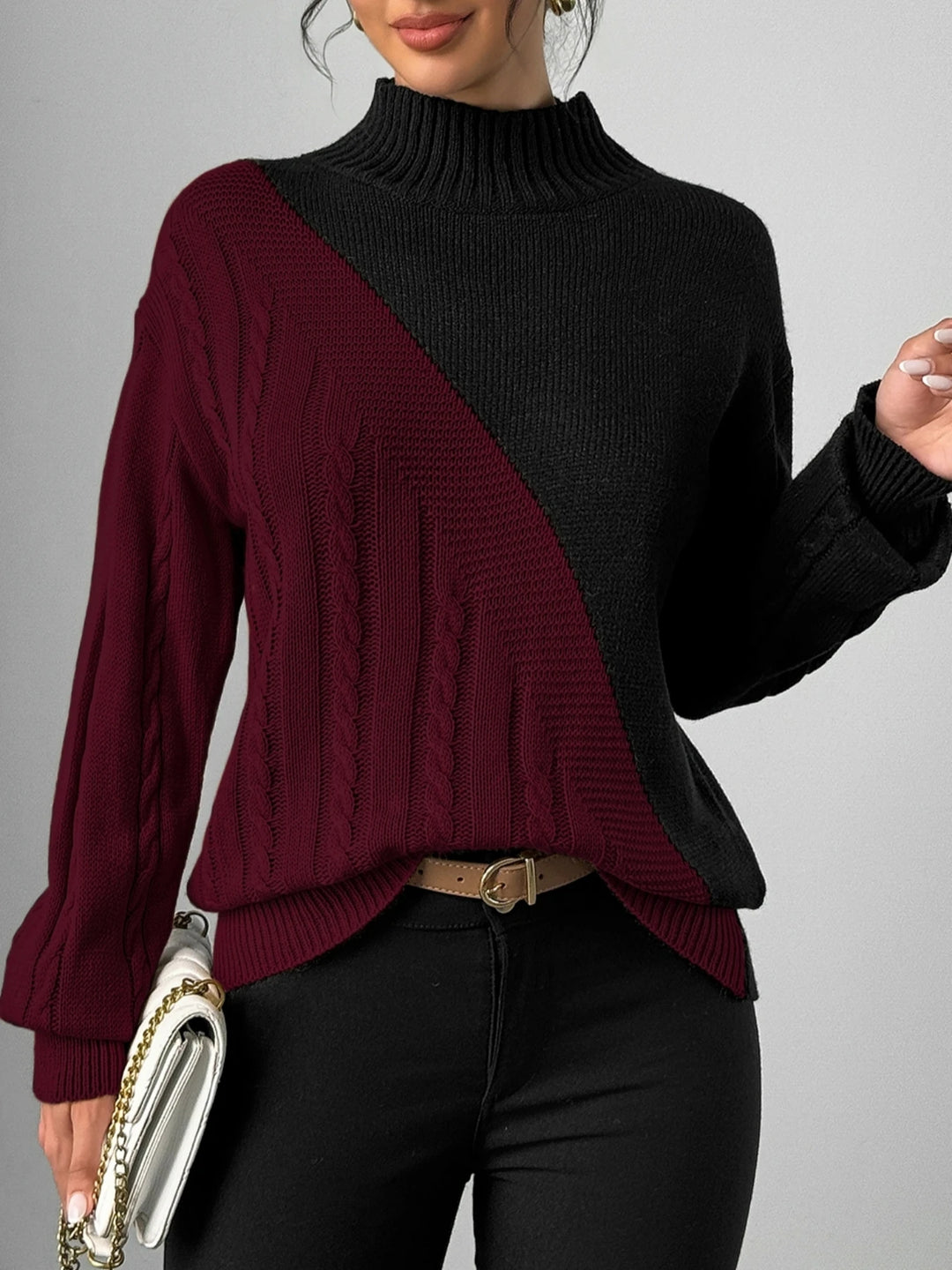Woman wearing burgundy and black color block cable knit mock neck sweater, front view