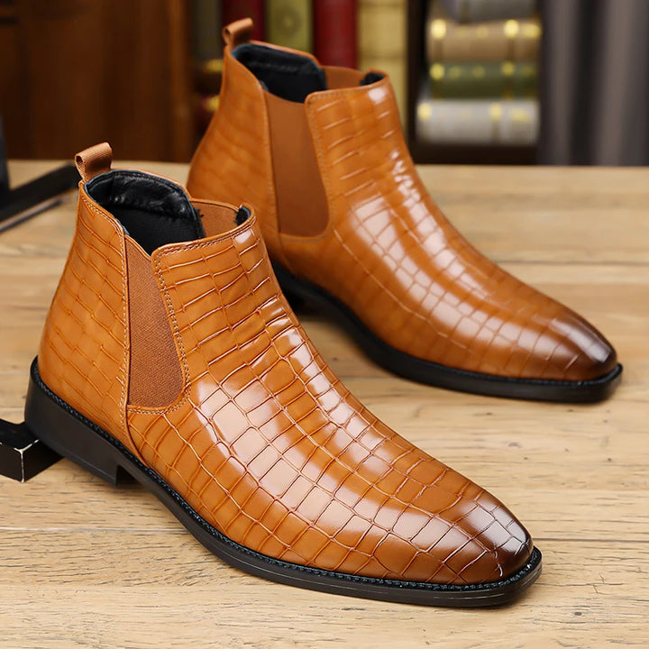 Pair of brown croc-embossed Chelsea boots on wood surface