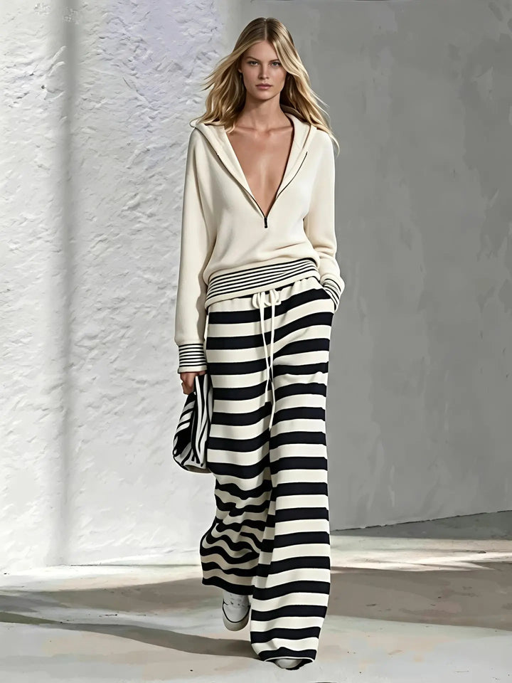 Woman wearing cream half-zip hoodie with black and white striped wide leg pants, front view