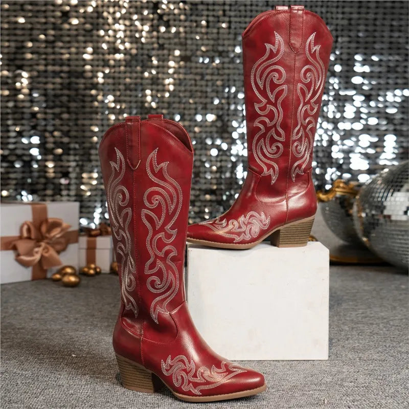 Red embroidered cowboy boots displayed on white pedestal
