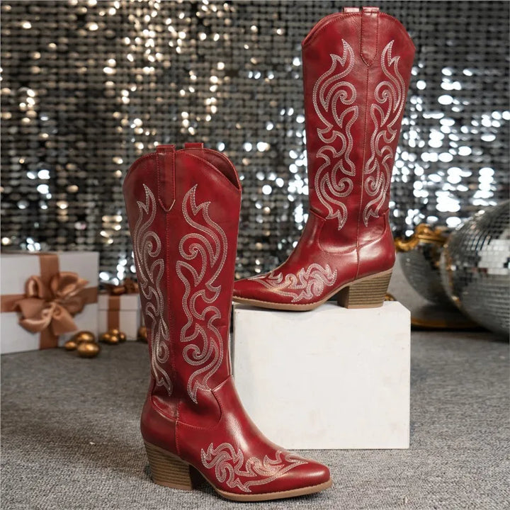 Red embroidered cowboy boots displayed on white pedestal