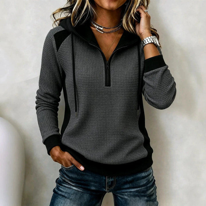 Woman wearing dark grey waffle knit half zip hoodie with black contrast panels