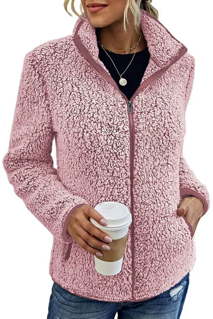 Woman wearing pink sherpa fleece zip jacket holding coffee