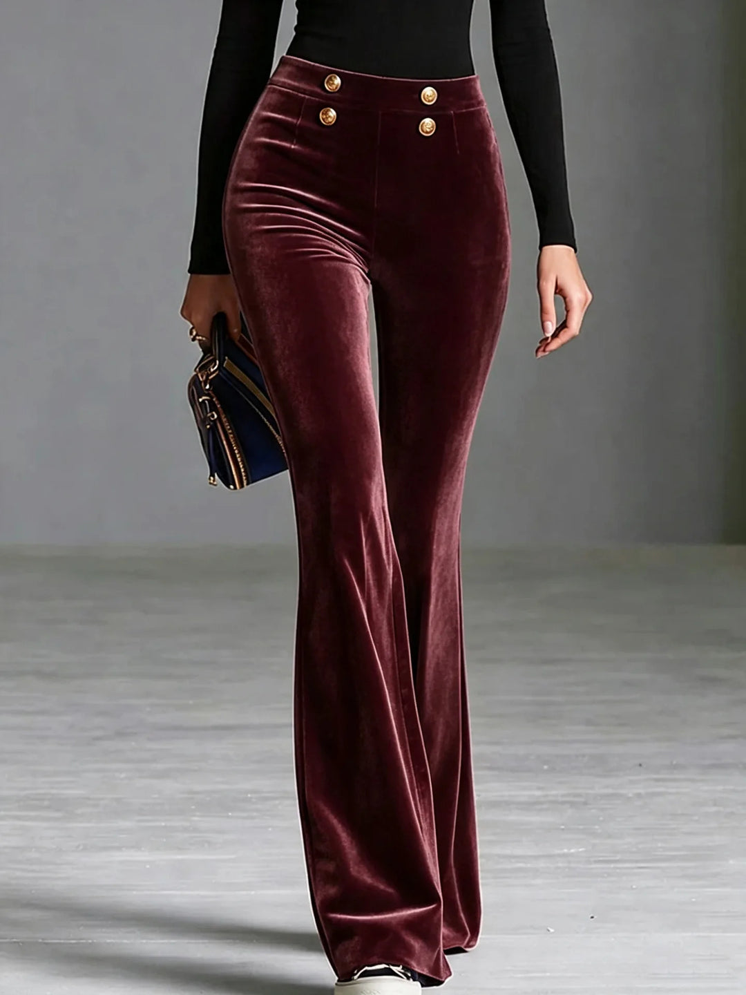 Woman wearing burgundy velvet flared high waist pants with gold buttons, front view