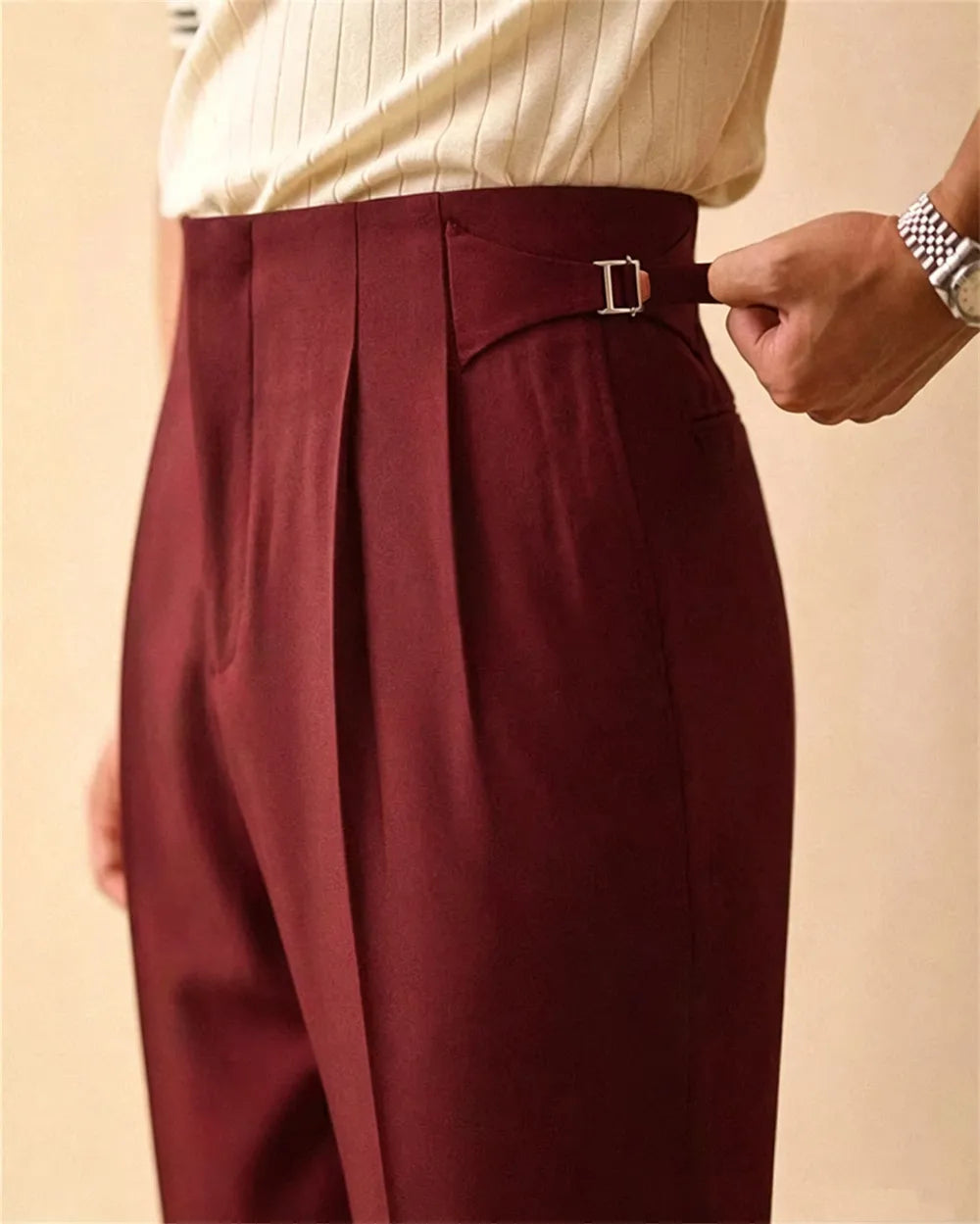 Close up of burgundy trousers with side tab buckle detail
