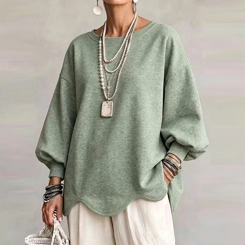 Woman wearing sage green oversized sweatshirt with wavy hem