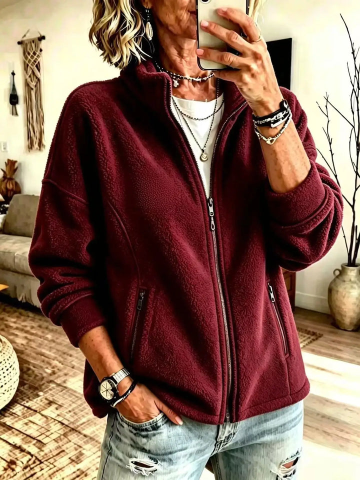 Woman wearing burgundy fleece full zip jacket with stand collar