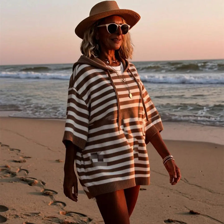 Woman wearing brown striped hooded sweater on beach at sunset