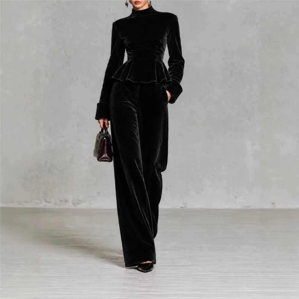 Woman wearing black velvet peplum top and wide leg pants set, front view