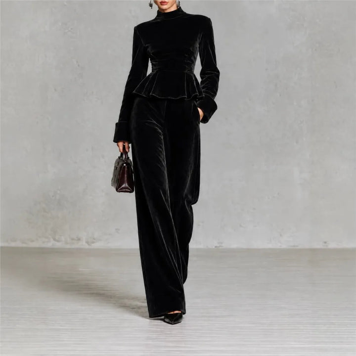 Woman wearing black velvet peplum top and wide leg pants set, front view