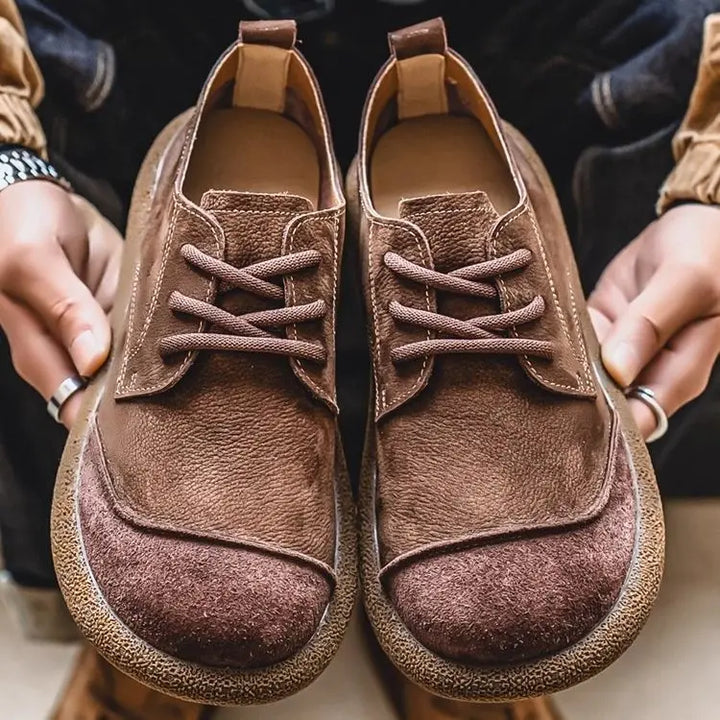 Brown moc toe lace up shoes held in hands, front view