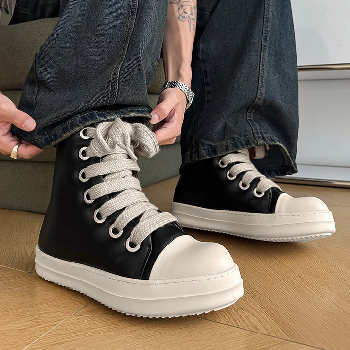 Side view of black high top sneakers with thick rope laces worn with jeans