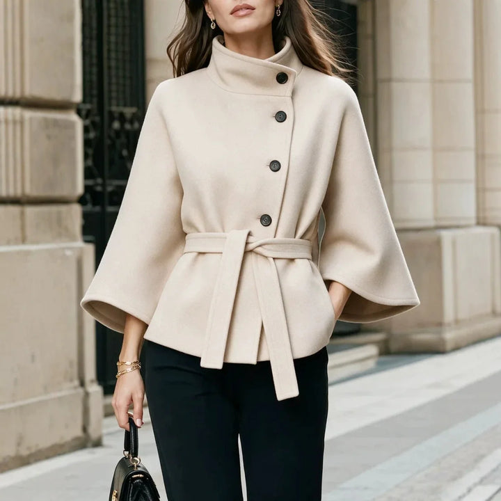 Woman wearing beige belted cape coat with stand collar