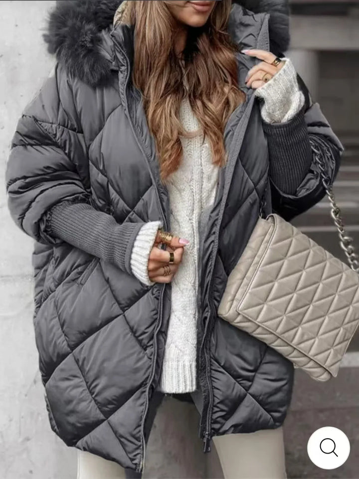 Woman wearing charcoal grey diamond quilted puffer coat with faux fur hood