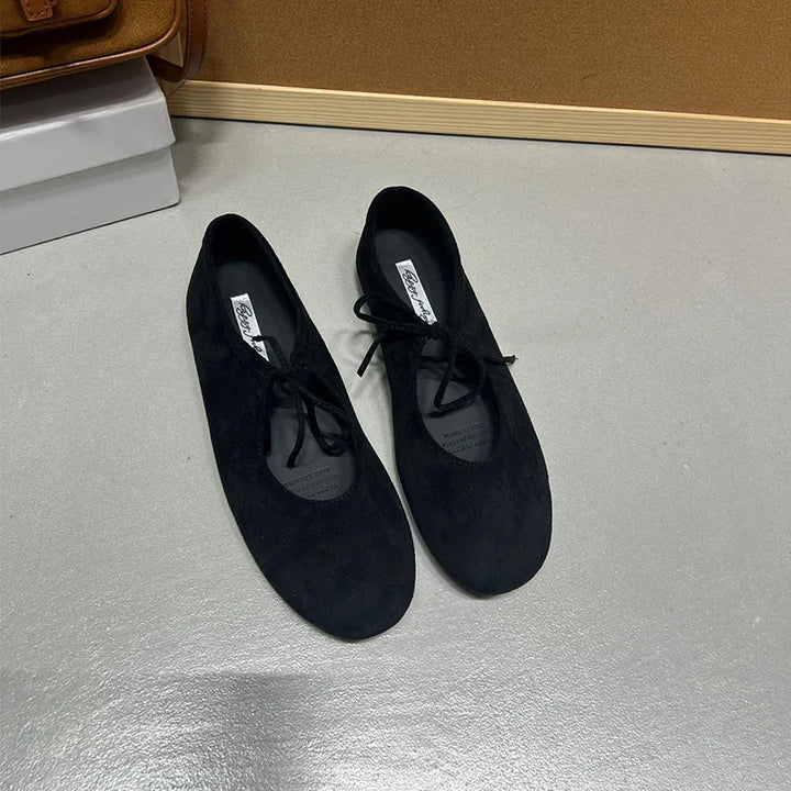 Black suede-look ballet flats with butterfly-knot ties, top view