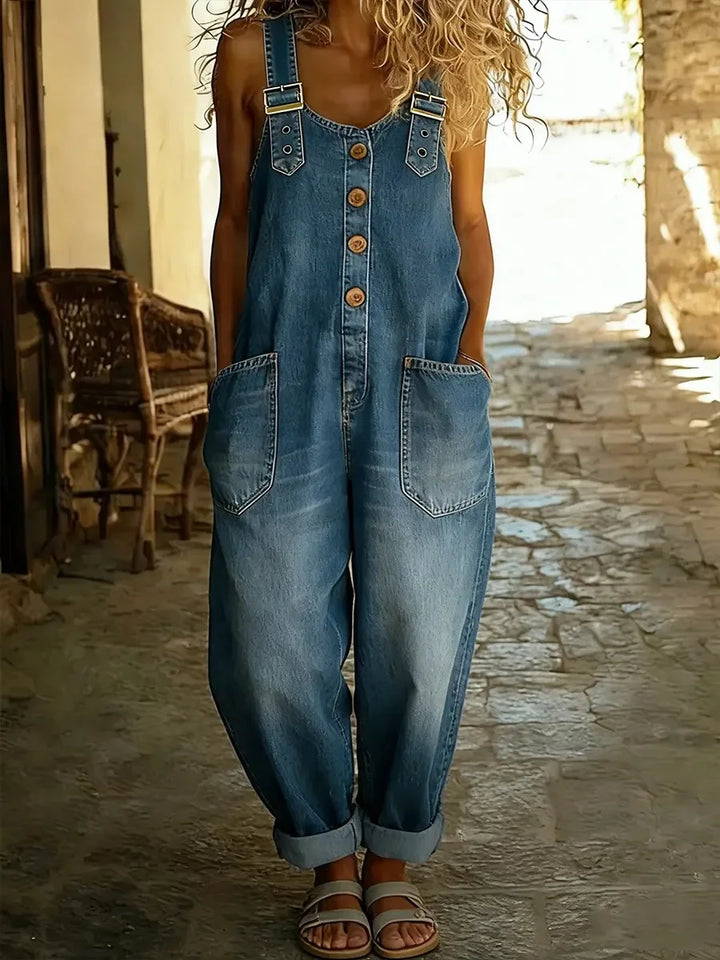 Close view of medium wash denim overalls with button front and buckle straps