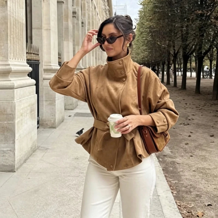 Woman wearing camel belted jacket walking outdoors
