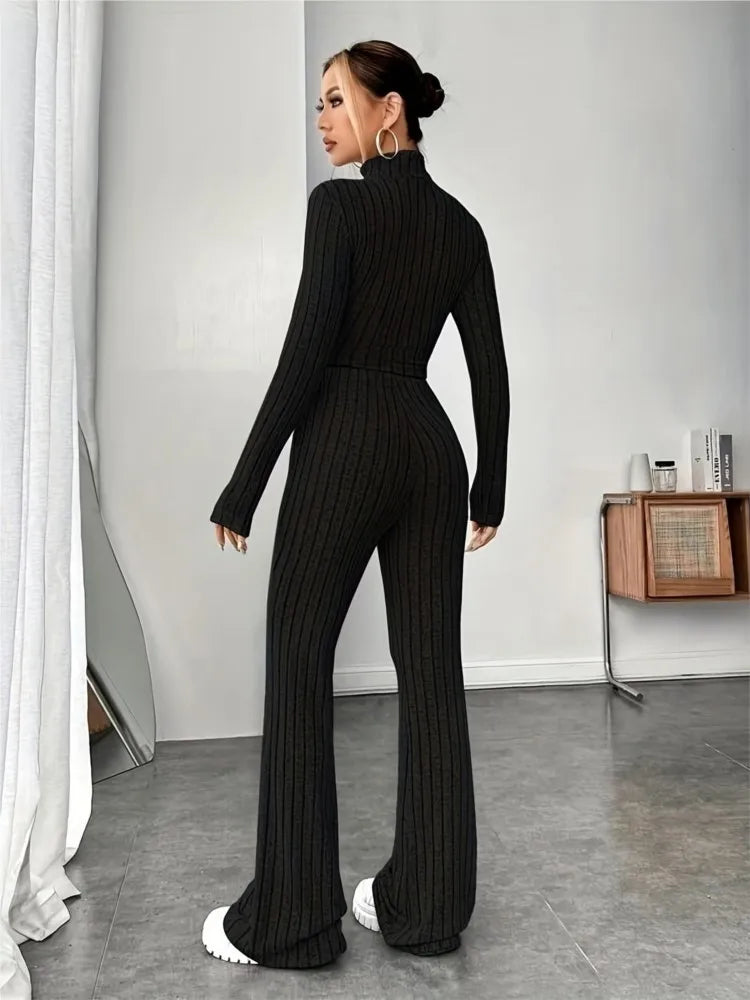 Woman wearing black ribbed knit crop top and flare pants set, back view