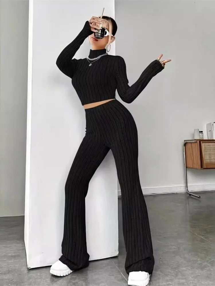 Woman wearing black ribbed knit crop top and flare pants set, front view