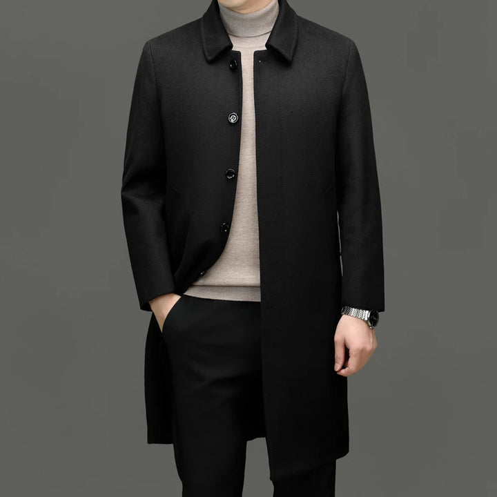 Man wearing black wool coat, front view with hand in pocket