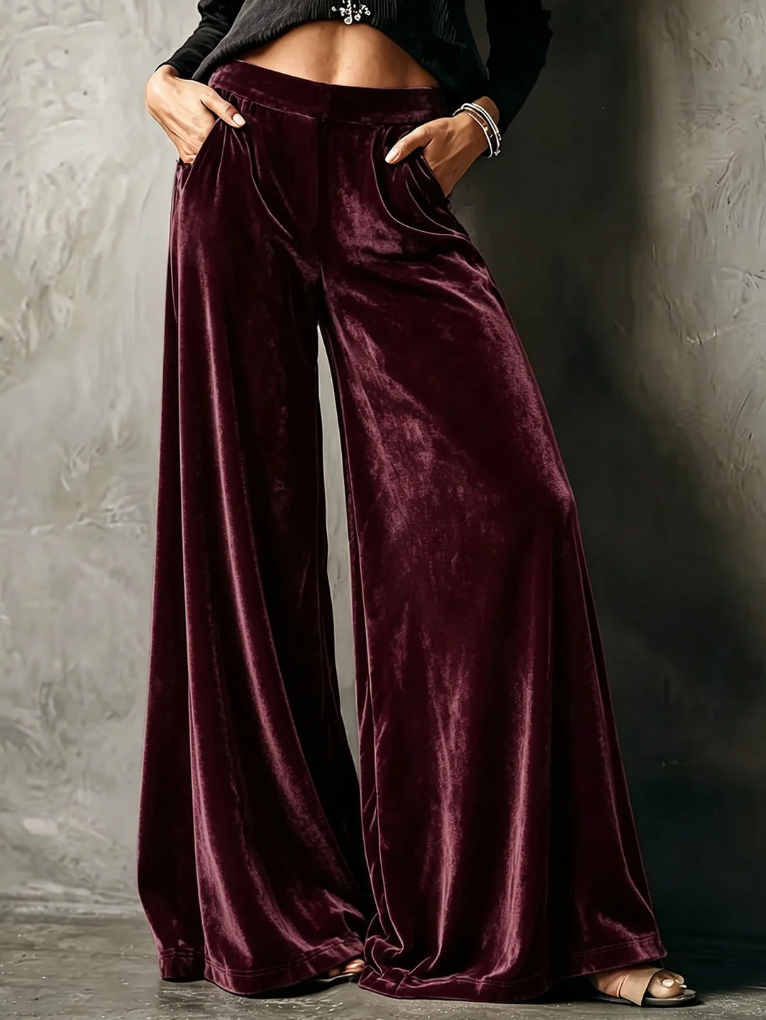 Woman wearing burgundy velvet wide leg pants with hands in pockets