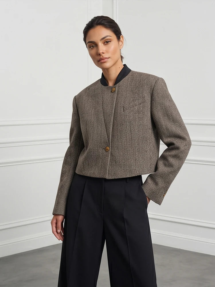 Woman wearing grey herringbone cropped jacket with black wide leg trousers, front view