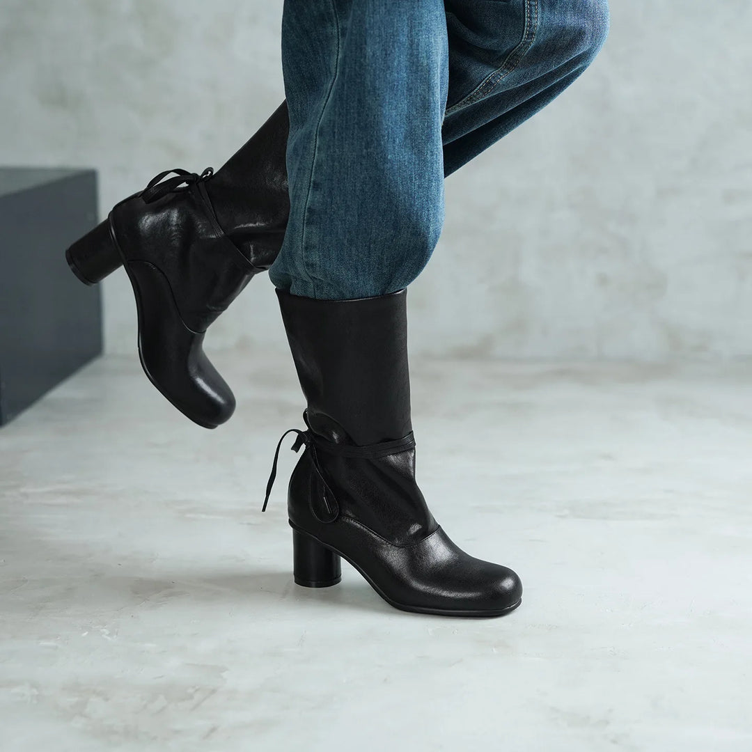 Model wearing black mid-calf boots with ankle tie, side view
