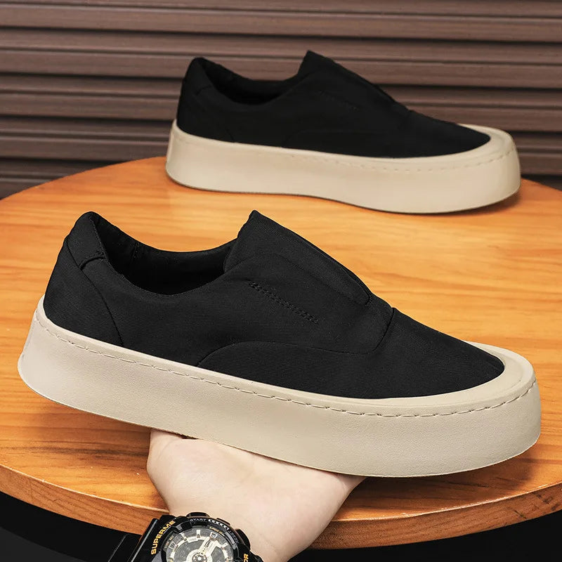 Black canvas slip-on sneakers on wooden table