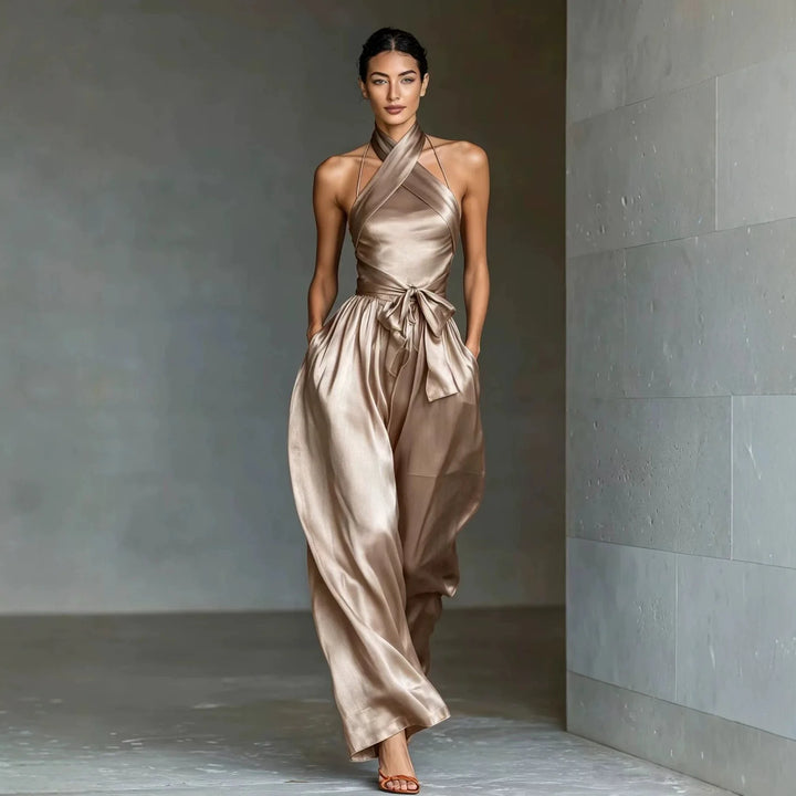Woman wearing champagne satin halter jumpsuit with tie waist