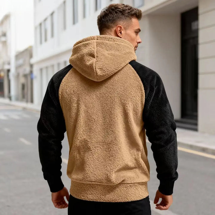 Back view of khaki and black sherpa hoodie on model walking outdoors