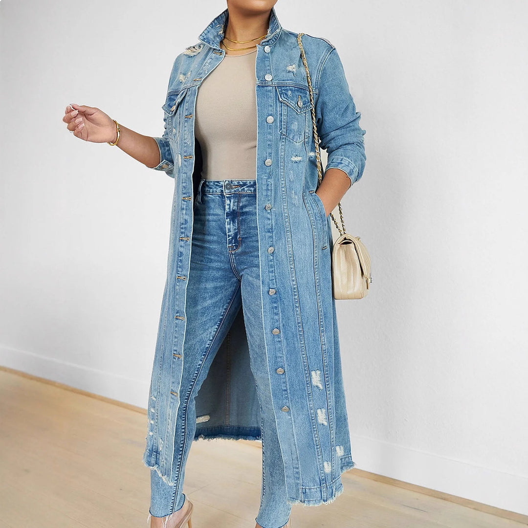Woman wearing long distressed denim trench coat over jeans