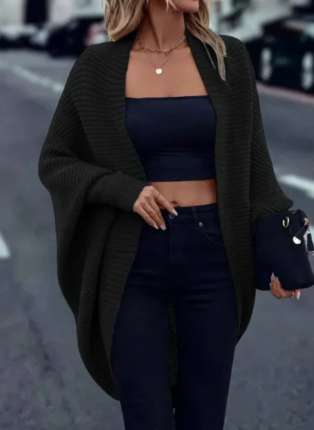 Woman wearing black ribbed knit open cardigan over black crop top