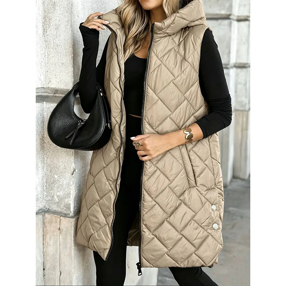 Woman wearing khaki quilted long puffer vest with hood, holding black bag