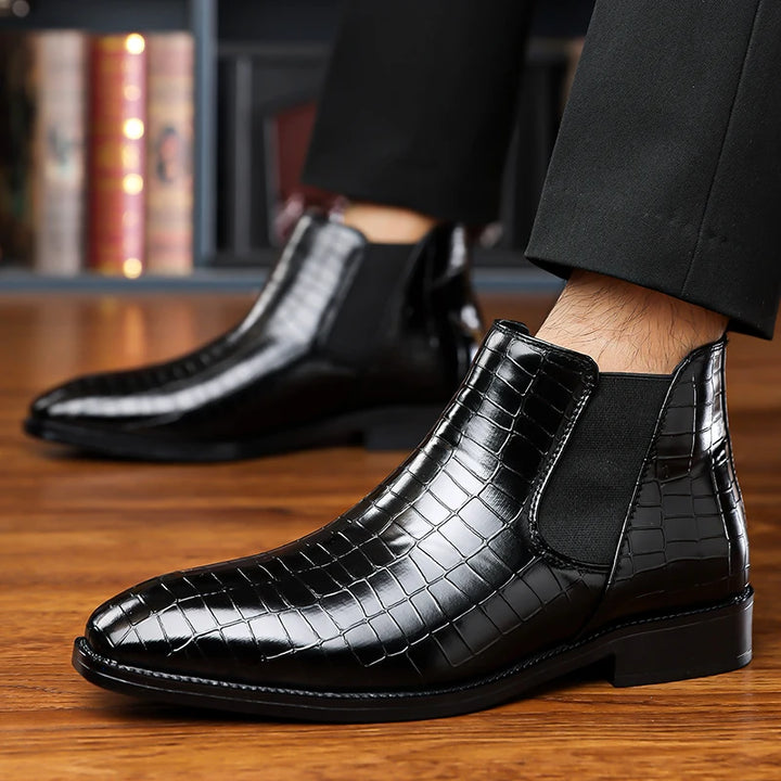 Black Chelsea boots worn with black trousers, side view
