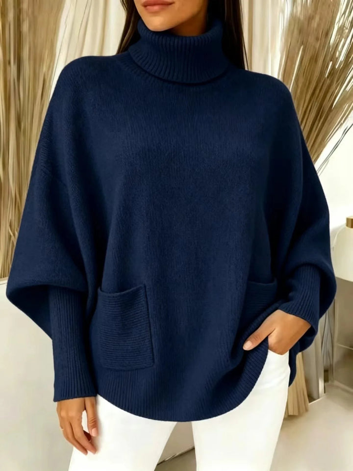 Woman wearing navy blue turtleneck batwing sweater with front pocket