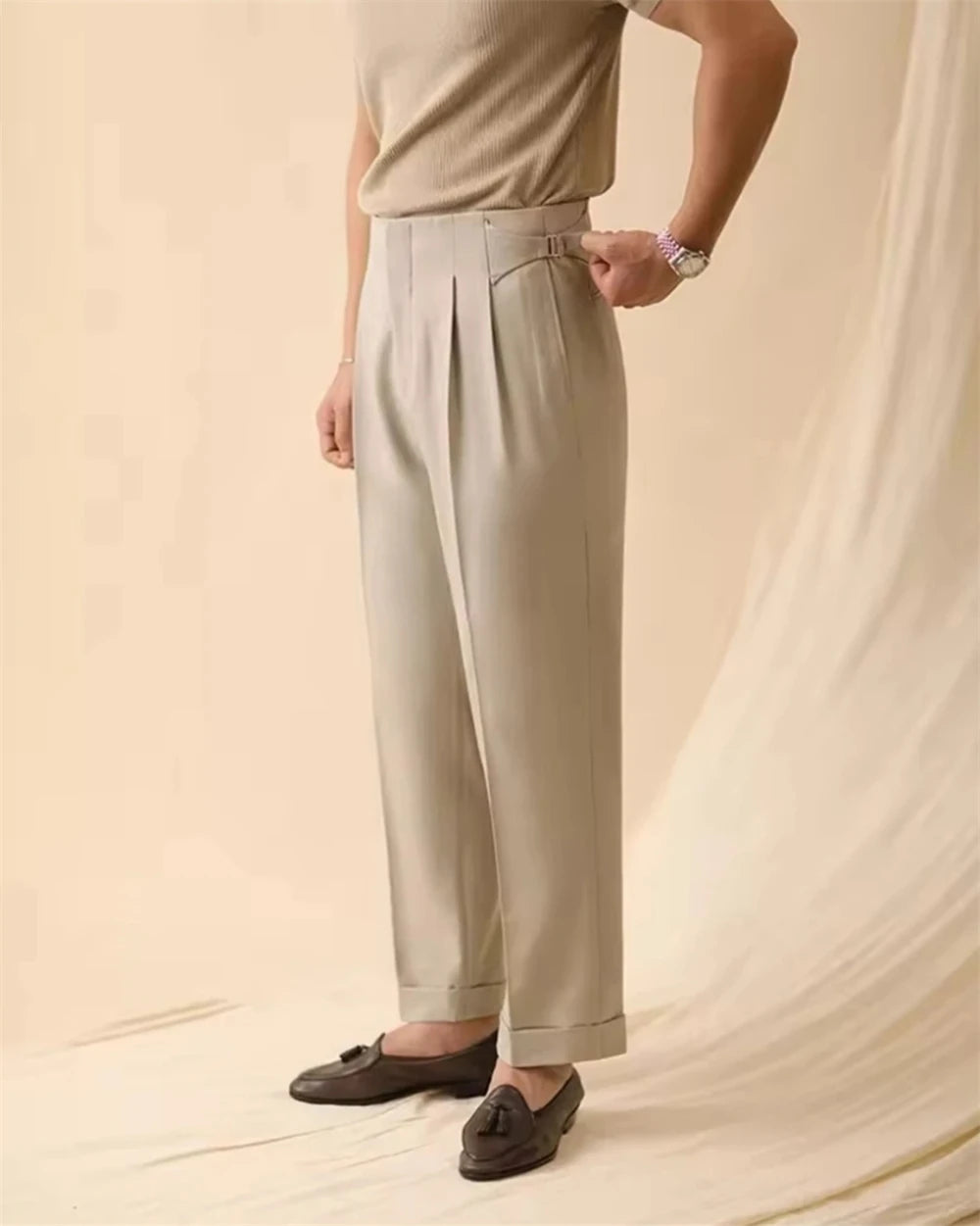 Man wearing beige cuffed trousers with loafers, side view