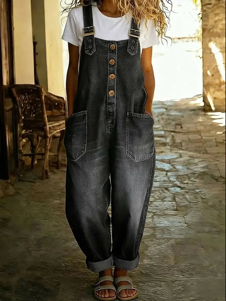 Dark wash denim overalls with buckle straps and cuffed ankles