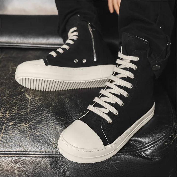 Black high top sneakers worn with black pants, close side view