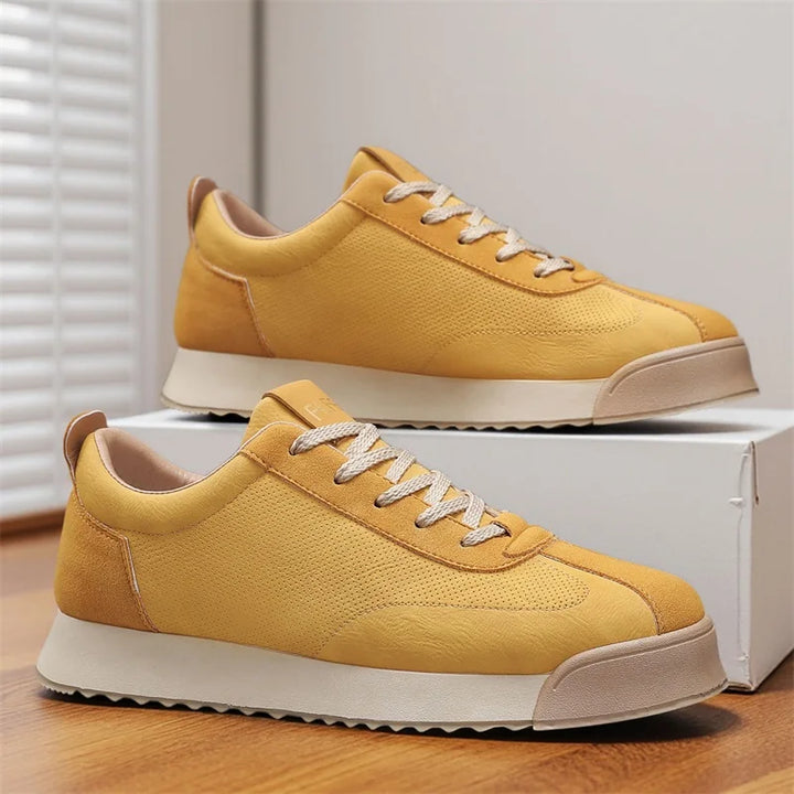 Pair of yellow low top sneakers with white sole shown beside shoe box