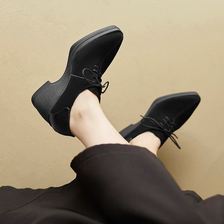 Black suede lace-up wedge pumps worn, crossed legs view