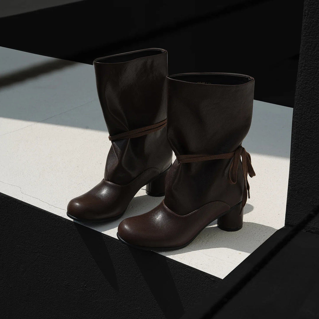 Pair of brown leather mid-calf boots on concrete step