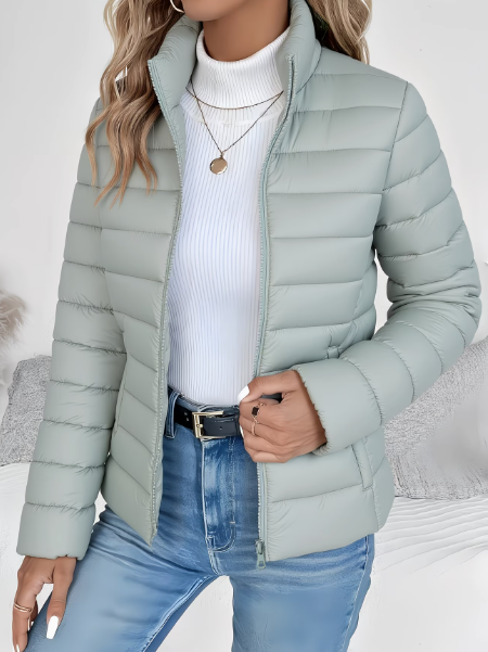 Woman wearing sage green quilted puffer jacket with stand collar, zipped open