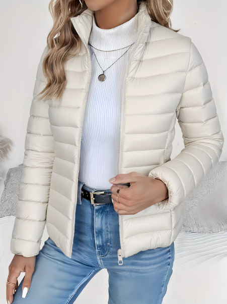 Woman wearing cream quilted puffer jacket with stand collar, zipped open