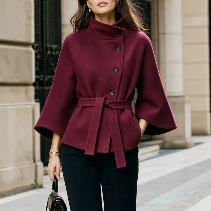 Woman wearing burgundy belted cape coat with stand collar