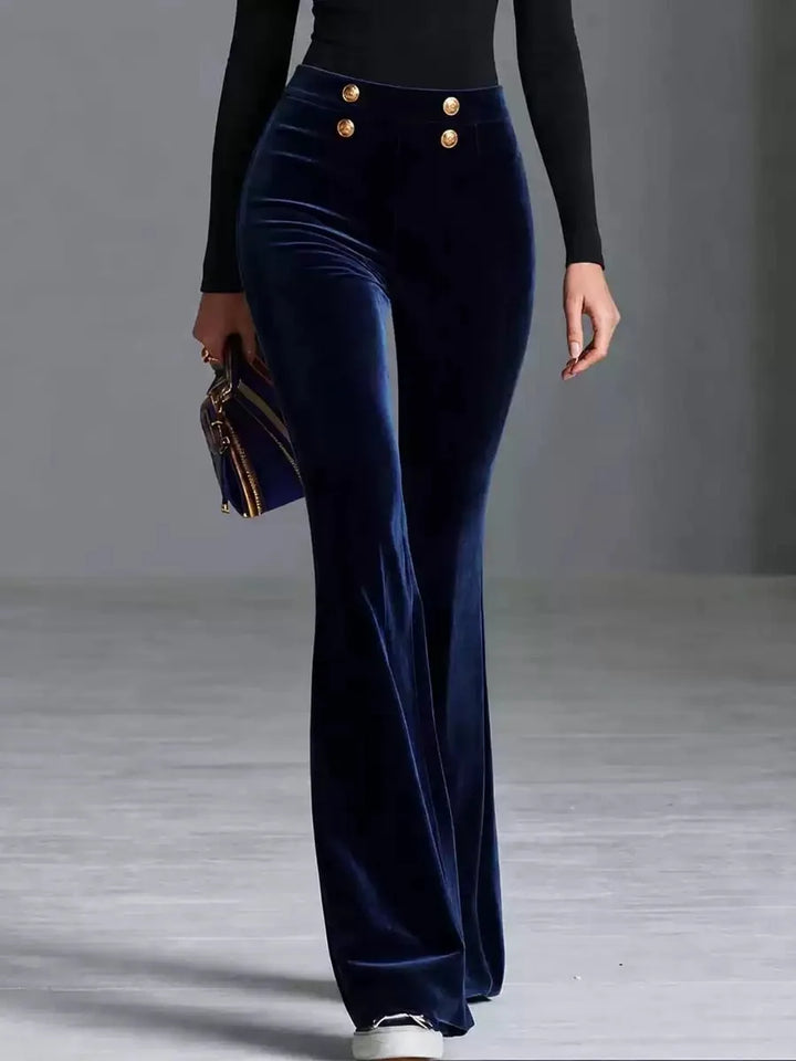 Woman wearing deep blue velvet flared high waist pants with gold buttons, front view