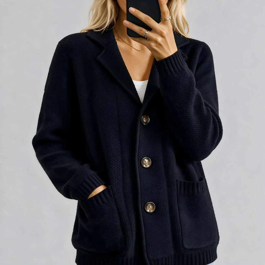 Close up of black cardigan with tortoiseshell buttons and patch pockets