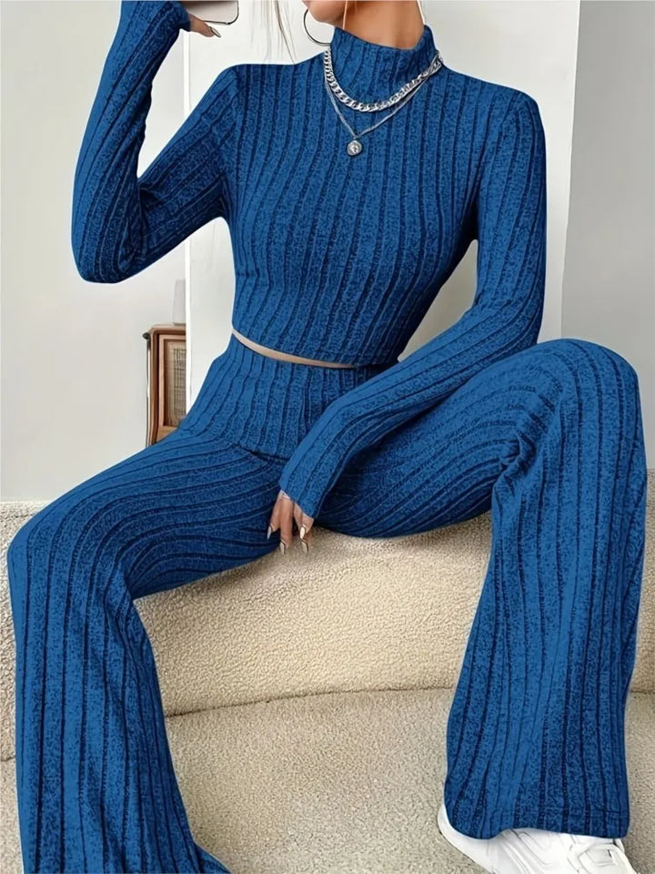 Woman seated wearing blue ribbed knit crop top and flare pants set
