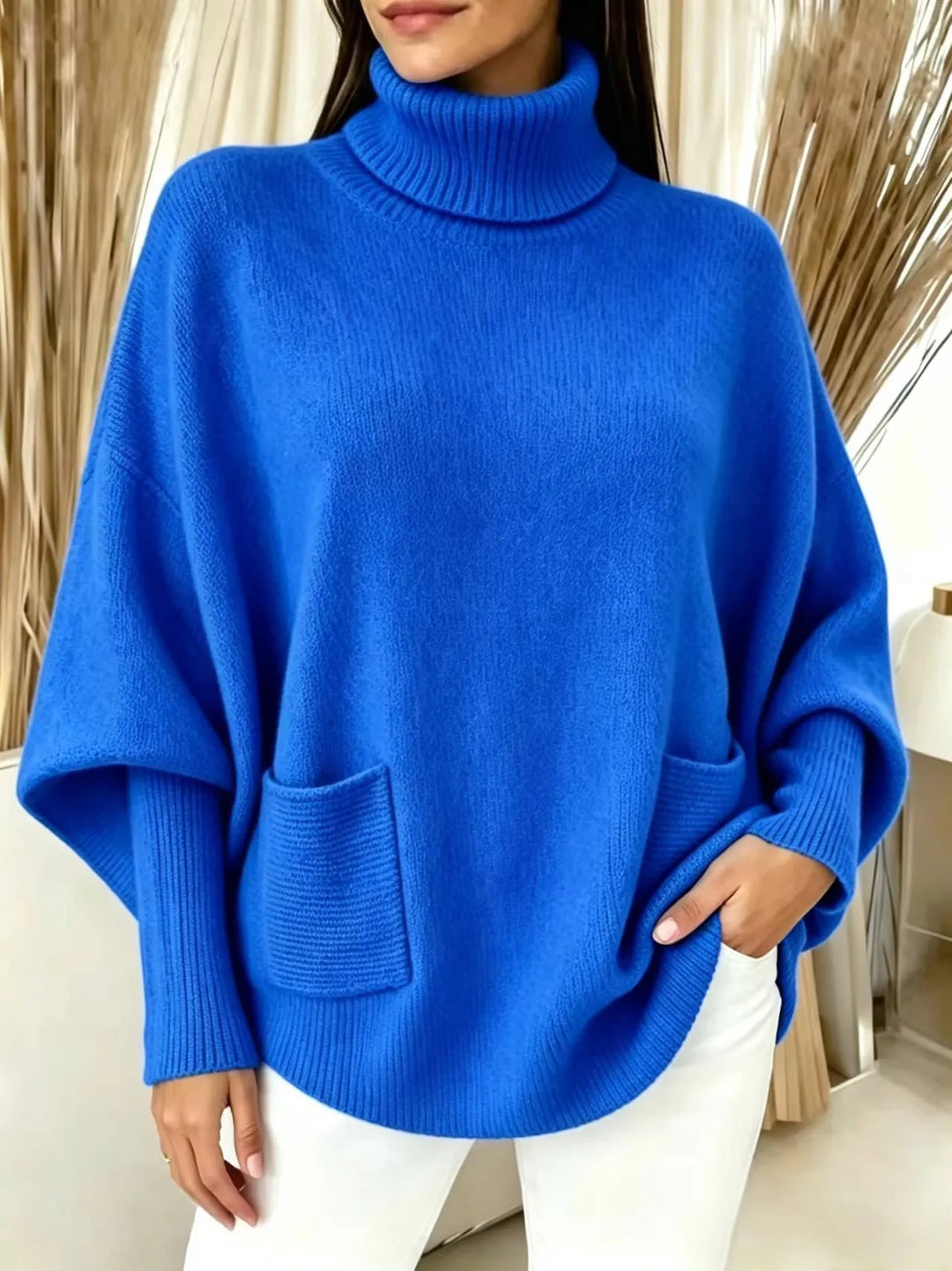 Woman wearing royal blue turtleneck batwing sweater with front pocket