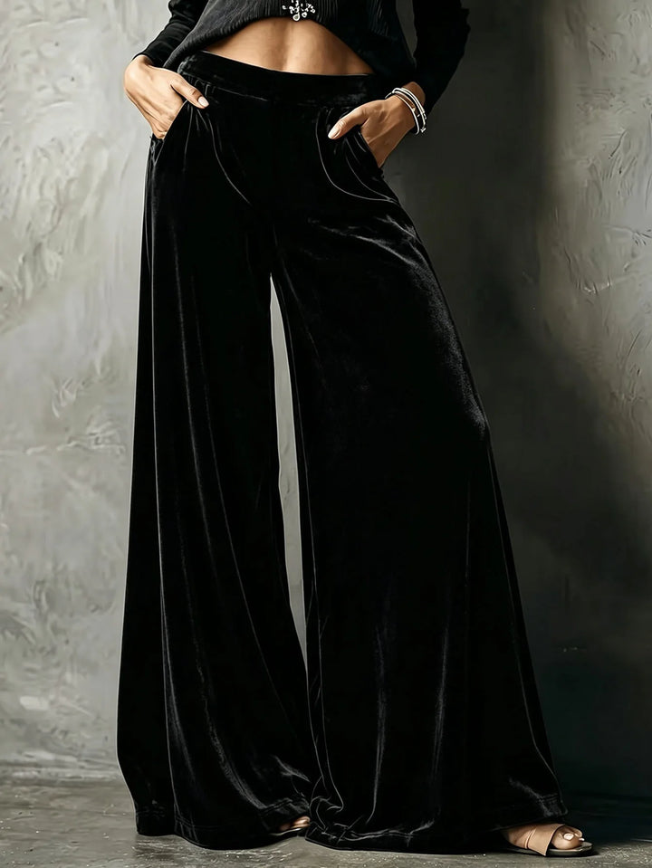 Woman wearing black velvet wide leg pants with hands in pockets